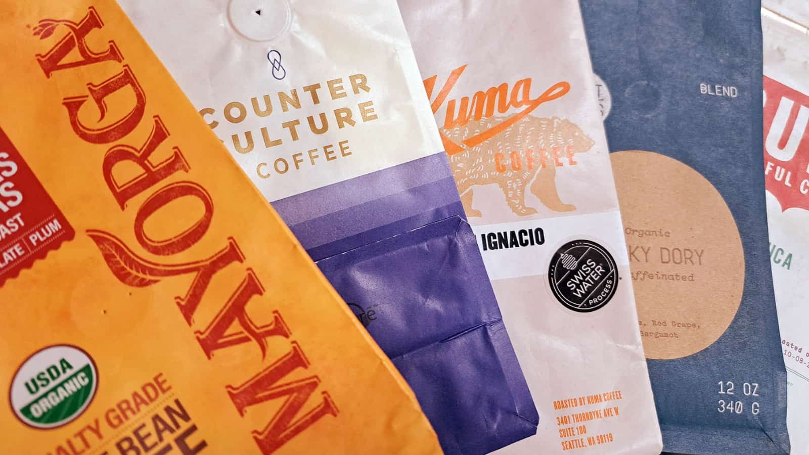 an array of empty coffee bags from coffee roasters such as Mayorga coffee, Counter Culture coffee, and Kuma coffee