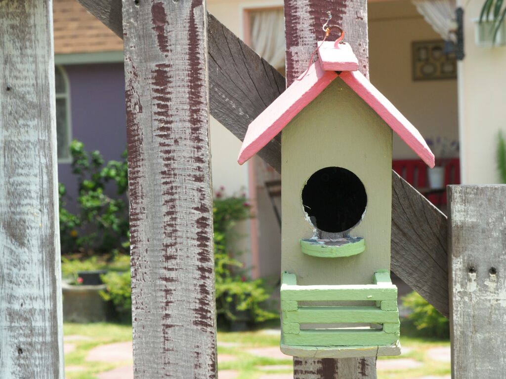 Old bird house or nest box hangs on the wooden fence